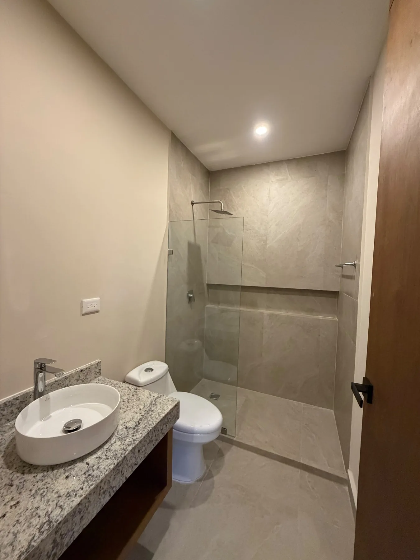 Segunda fotografía real del baño del departamento muestra de Alma Condos, con regadera, nicho y fijo de cristal.