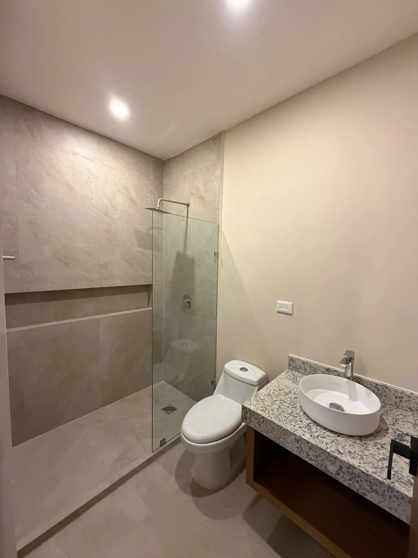 Fotografía real del baño del departamento muestra de Alma Condos, con lavabo sobre cubierta, WC y regadera con fijo de cristal.