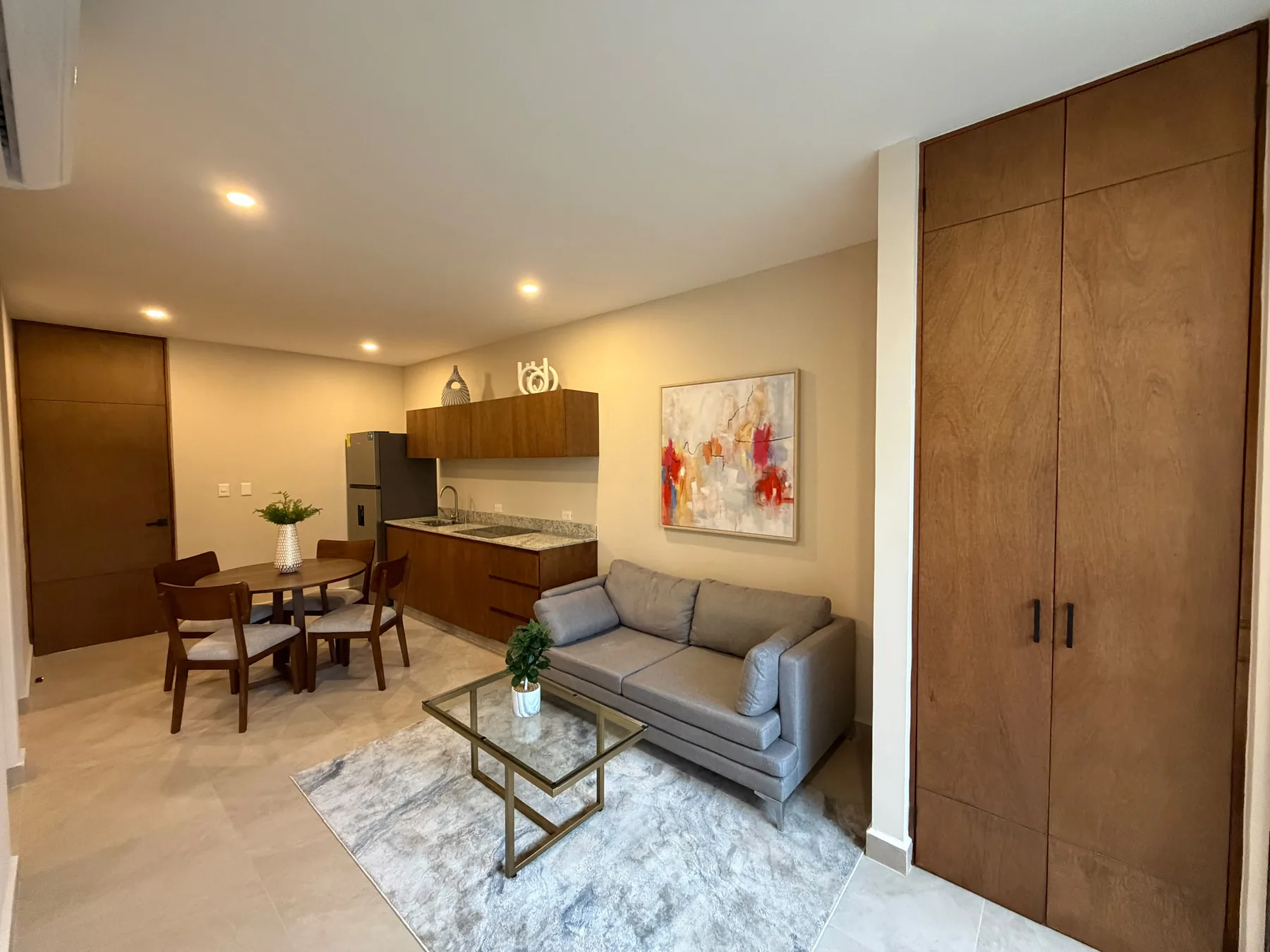 Fotografía real del área social del departamento muestra de Alma Condos, con sala, comedor y cocina abierta.